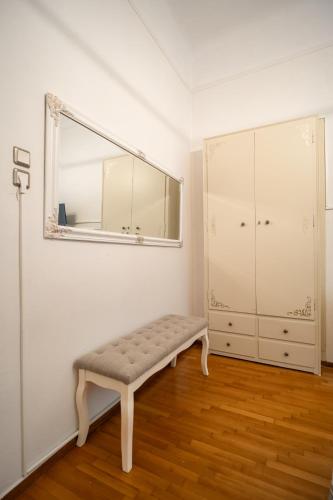 a white room with a bench and a mirror at The Rock Guesthouse in Kalabaka