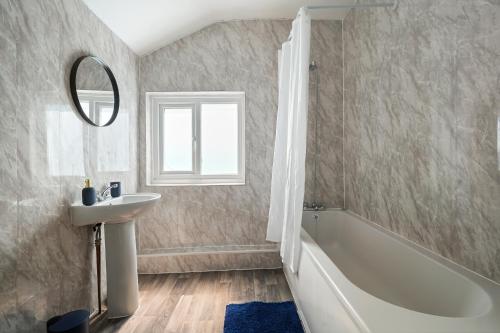 ein Badezimmer mit einem Waschbecken, einer Badewanne und einem Spiegel in der Unterkunft Brun Clair House in Chatham