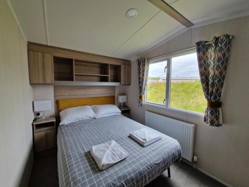a small bedroom with a bed and a window at Machrihanish Holiday Park in Campbeltown