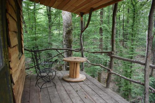 un porche de una cabaña con mesa y sillas en La cabane aux écureuils en Philippeville