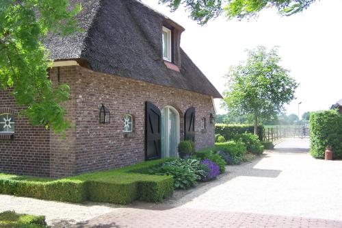 a brick house with a thatched roof at B&B Farmhouse De Loksheuvel in Overasselt