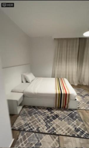a bedroom with a white bed and a rug at شاليه فندقي بحمام سباحه خاص داخل فندق ايليت ريزيدنس اند اكوا بارك in Ain Sokhna