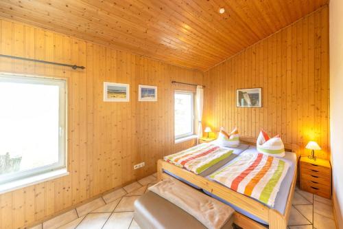 1 dormitorio con 1 cama en una pared de madera en Ferienhäuser Suhrendorf en Ummanz