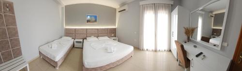 a white room with two beds and a mirror at Hotel Kolla in Derviçian