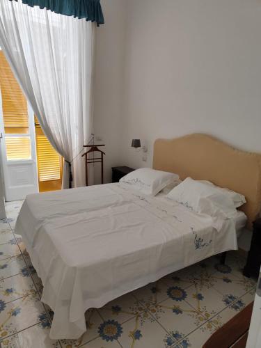 Schlafzimmer mit einem Bett mit weißer Bettwäsche und einem Fenster in der Unterkunft The House Of The Sunbeam in Neapel