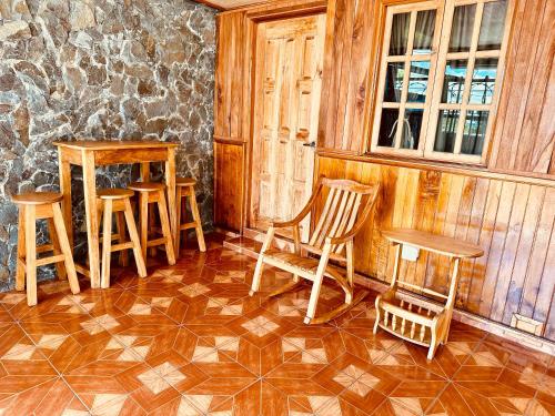 a room with wooden chairs and tables and a stone wall at Residencial Coya in David