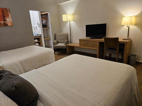 a hotel room with two beds and a desk with a television at Bluu Hotel Aeropuerto Monclova-Frontera in Monclova