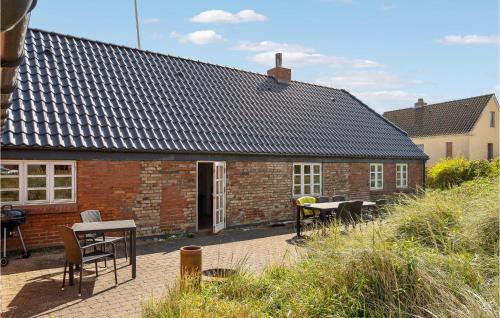 a brick house with tables and chairs in front of it at Beautiful Home In Thyborøn With Sauna in Thyborøn