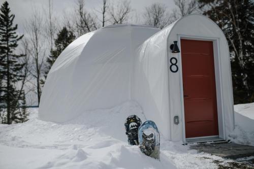 una tabla de snowboard está de pie en la nieve frente a un iglú en Station Boréale en Val-dʼOr