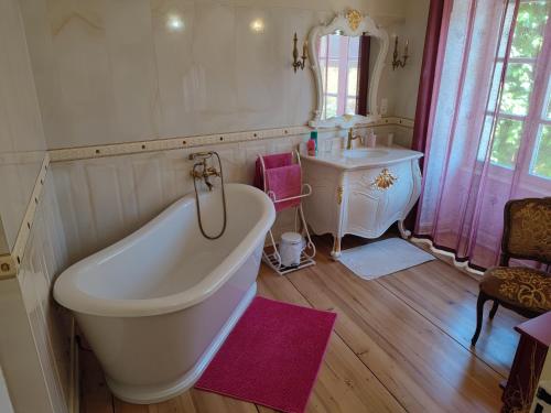 a bathroom with a large tub and a sink at Demeure d'antan in Beblenheim