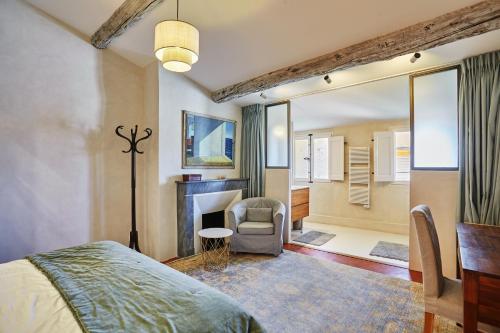 - une chambre avec un lit, une chaise et une cheminée dans l'établissement Les suites de Montigny, à Aix-en-Provence