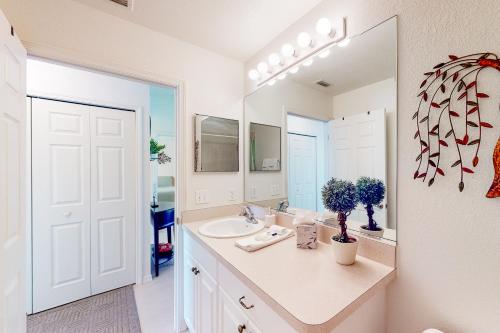 Baño blanco con lavabo y espejo en Sunny Way, en Rotunda-West