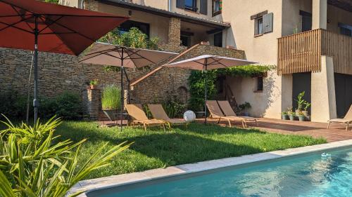 un patio con sillas y sombrillas y una piscina en CASA AUGUSTA, en Riez