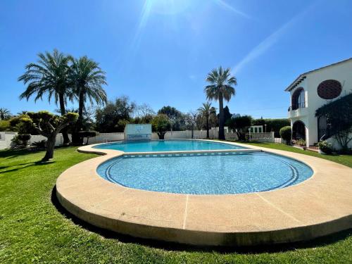 - une piscine dans une cour avec des palmiers dans l'établissement Apartamento Cabañas 1, à Dénia
