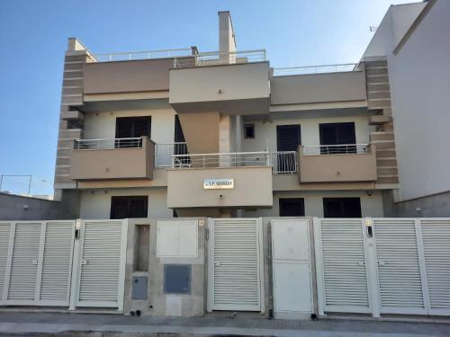 切薩雷奧港的住宿－Kennedy Apartments- Porto Cesareo，一座带白色门和栅栏的建筑