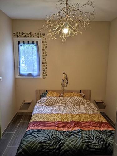 une chambre avec un lit et un lustre dans l'établissement Au soleil couchant, à Villemoustaussou