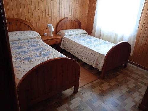 2 Betten in einem Zimmer mit Holzwänden in der Unterkunft Casa Puerta del Sol in Moaña