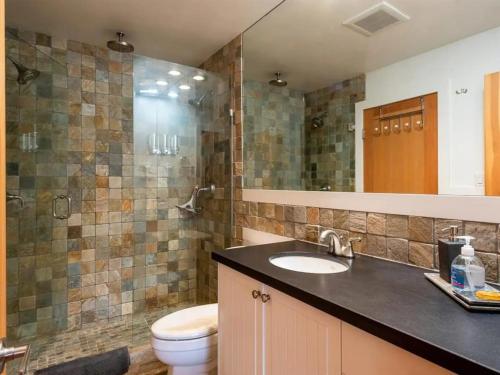 y baño con aseo, lavabo y espejo. en Stunning 2BR w Pool, Hot Tub Walk to everything! en Whistler