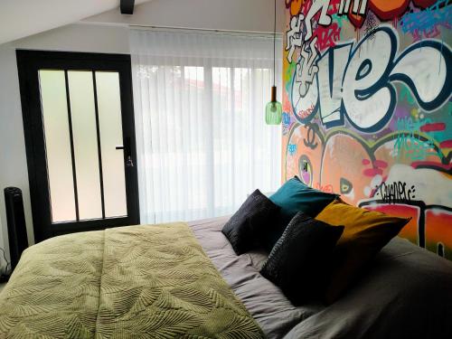 a bedroom with a bed with a wall with graffiti at Chambre Street Art in Capbreton