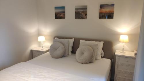 a bedroom with a white bed with two lamps at Zeezicht vanop het 6 de verdiep in Oostduinkerke