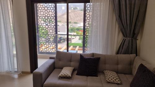 a living room with a couch and a large window at Two bedroom Apartment Muscat Bay in Muscat