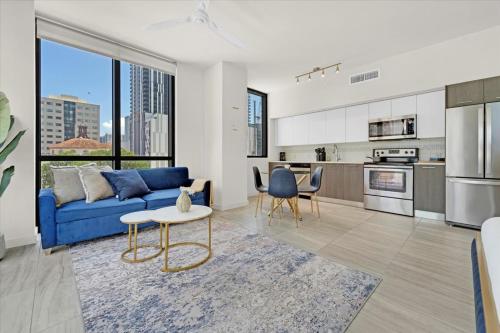 a living room with a blue couch and a kitchen at Devereaux Miami Luxury One-Bedroom and Studios in Miami