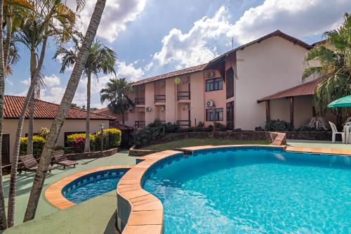 a swimming pool in front of a house with palm trees at Hotel Vivenda das Cachoeiras in Brotas