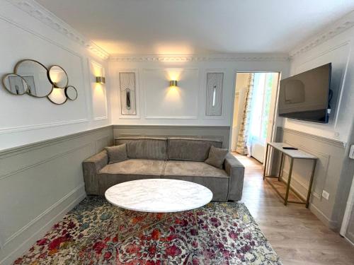een woonkamer met een bank en een tafel bij Suite Adèle Passy in Parijs