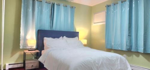 a bedroom with blue curtains and a bed with white sheets at Modern 2BR Apartment Jamaica Queens NYC in Hillside