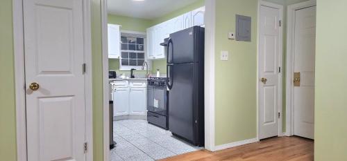a kitchen with a black refrigerator and white cabinets at Modern 2BR Apartment Jamaica Queens NYC in Hillside