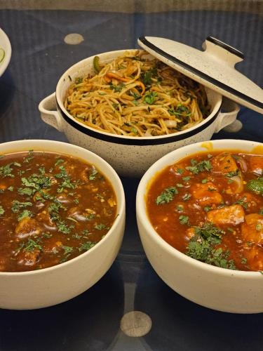 three bowls of soup and pasta on a table at Villa MYSA in Rāmgarh