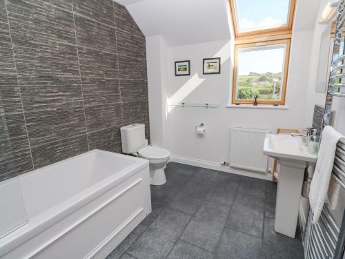 a bathroom with a tub and a toilet and a sink at Sandbanks in Penzance