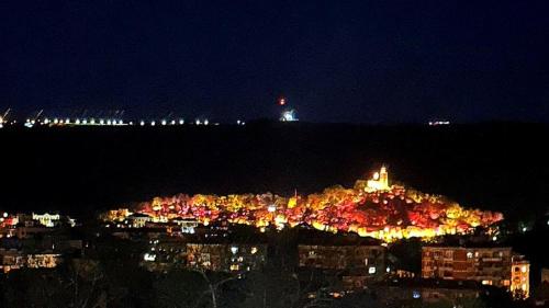 uma cidade iluminada à noite com um farol ao fundo em Tarnovo Studios City Center em Veliko Tarnovo