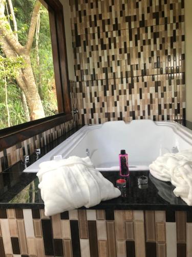 a bathroom with a bath tub with towels on a table at Pousada Vale dos Sonhos in Cunha