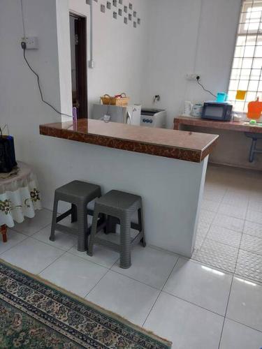 une cuisine avec deux tabourets assis à un comptoir dans l'établissement Homestay Kak Pah Kota Bahru, à Kota Bharu