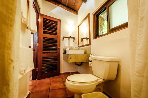a bathroom with a toilet and a sink and a window at Hotel Rancho Encantado in Bacalar