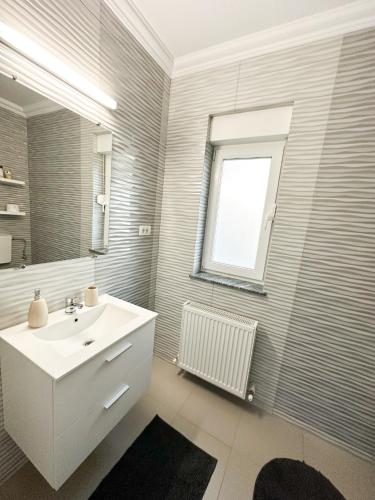 a white bathroom with a sink and a window at House Lake in Techirghiol