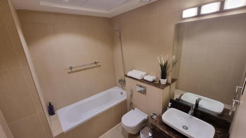 a bathroom with a tub and a toilet and a sink at Two bedroom Apartment Muscat Bay in Muscat