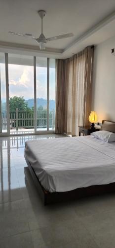 a bedroom with a large bed and large windows at The Cloud Hanthana, Kandy in Kandy