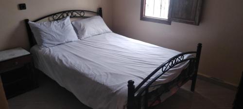 uma cama com lençóis brancos e almofadas num quarto em Appart avec terrasse El Ouatia Tan Tan Plage em Tan-Tan Plage