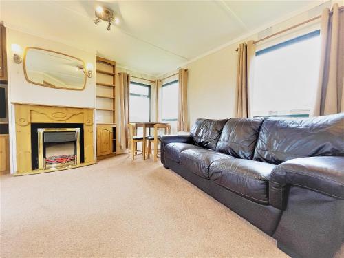 a living room with a leather couch and a fireplace at Barker Stakes Farm in Pickering