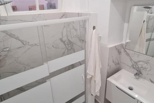 a white bathroom with a shower and a sink at Casa Aprosio, appartamento luminoso in centro a Ventimiglia, a 5 min dal mare e dal treno in Ventimiglia