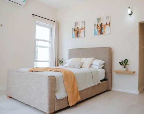 a bedroom with a bed with white walls and a window at Blissful Tides in Hope Bay