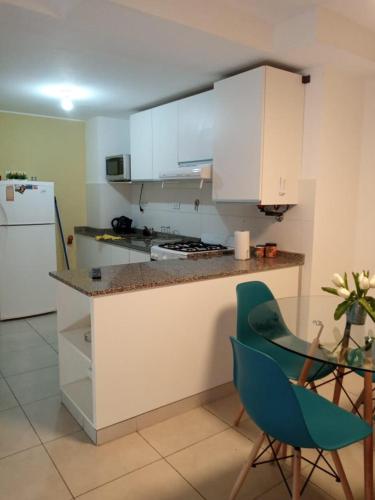 uma cozinha com armários brancos e uma cadeira verde em Departamentos NG CENTRO Carlos Paz em Villa Carlos Paz