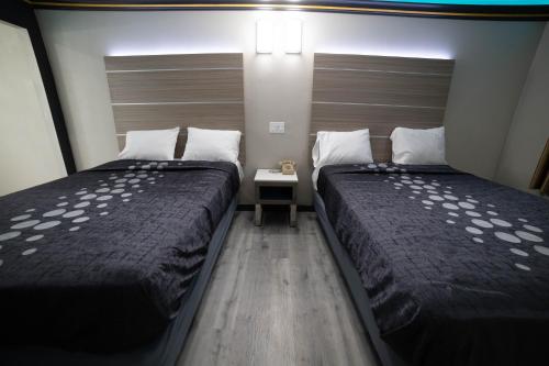 duas camas num pequeno quarto com saias em Artesia Motor Inn em Bellflower