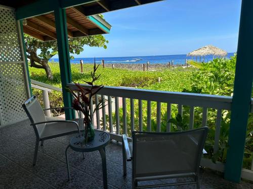 a porch with chairs and a table with a view of the beach at Seagrape Plantation Resort & Dive Center in West End