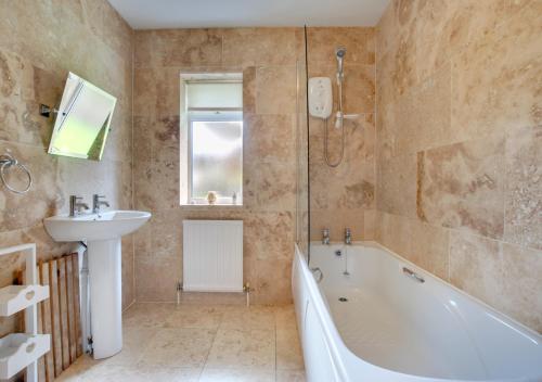 a bathroom with a bath tub and a sink and a bath tub at Castle View in Saundersfoot