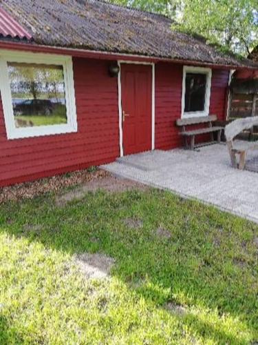 a red house with a bench in front of it at Kempings Mežmalas in Usma
