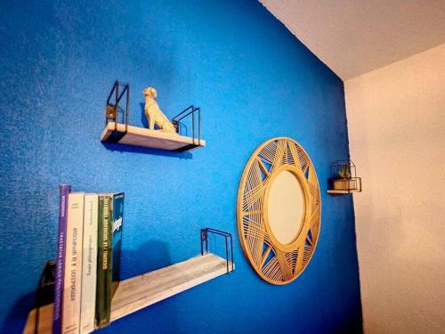 a blue wall with a shelf and a mirror and books at Le Libé 206 - Quartier libération - Centre Ville in Nice