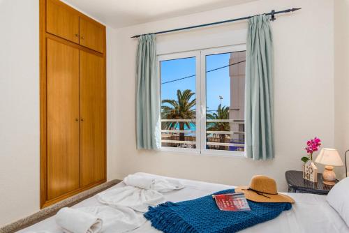 een slaapkamer met een raam en een bed met een hoed erop bij Apartamento Arenal 4 - PlusHolidays in Calpe